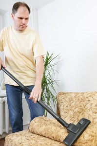 Man vacuums a sofa